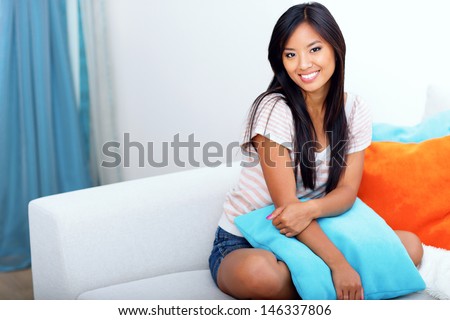 Beautiful asian woman in casual clothings sitting on the sofa at home