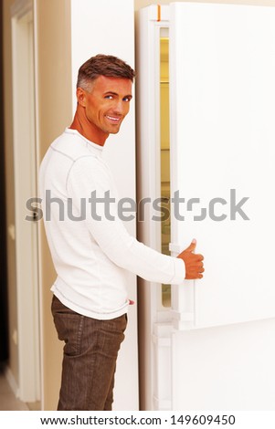 Handsome happy man opening the refrigerator