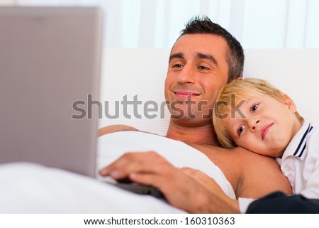 Father and son in bed, using laptop together