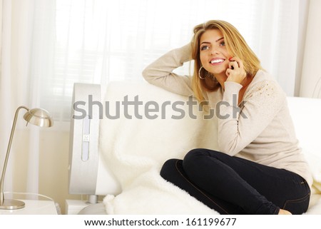 Happy woman talking on phone at home