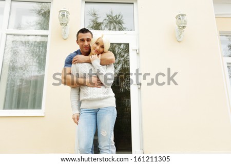 Happy couple standing in front of their new house