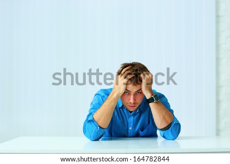 Young serious businessman sitting at the table in office