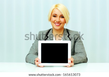 Young smiling businesswoman woman showing display of a tablet computer in office