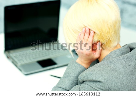 Young businesswoman having a headache at her workplace in office