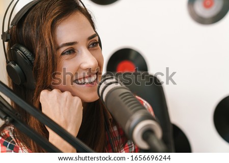 Smiling young woman radio host making podcast recording for online show 商業照片 © 