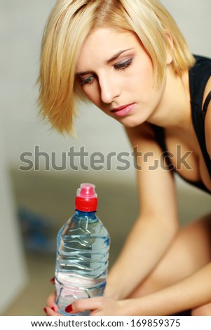 Closeup portrait of a young pensive woman with bottle of water
