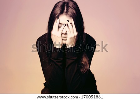 Black and white photo of a depressed young woman with hands over her head