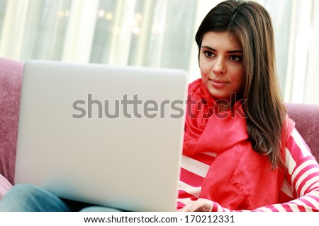 Young beautiful woman sitting on the sofa and using laptop at home