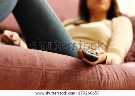 Closeup image of a female hand holding remote control