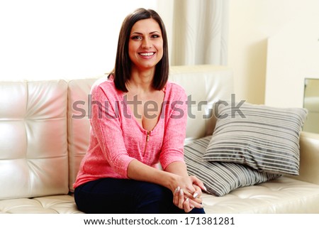 Young laughing woman sitting on the sofa at home