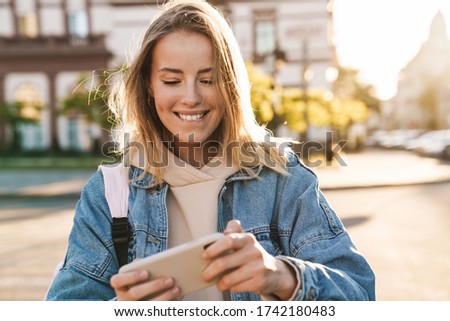 Image, Stock Photo Blonde woman wearing denim shirt and black leather skirt sitting in an urban bench.