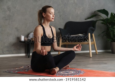 Attractive young healthy woman practising yoga on a mat in the studio, in a yoga position