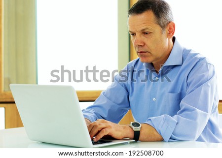 Portrait of a middle aged caucasian man looking at his laptop computer.