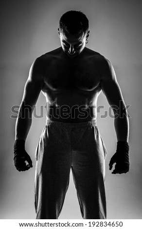 Naked sportsman standing with his hands wrapped with elastic bandage on gray background