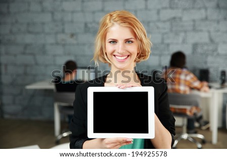 Young happy woman showing blank tablet computer screen in office