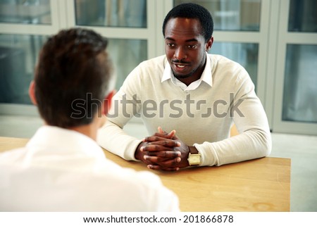 Two business people sitting at the table and talking in office