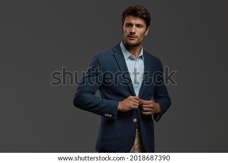 Young beautiful focused european businessman. Front view of bearded man with dark hair clothing casual jacket. Isolated on dark gray background. Studio shoot