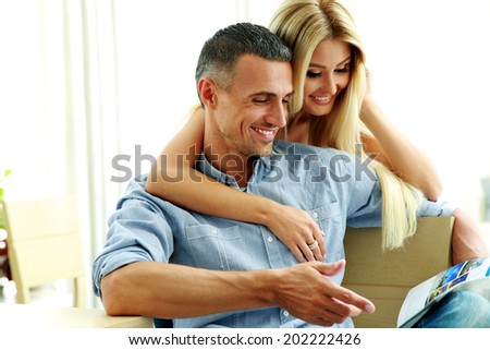 Young couple reading magazine at home