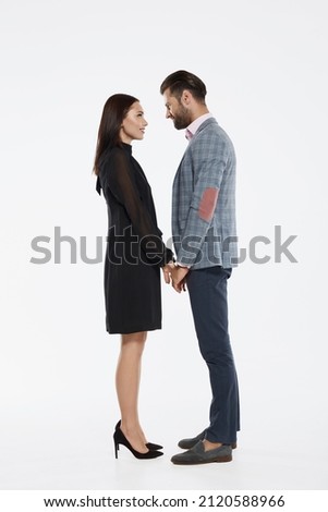 Young happy caucasian couple holding hands and looking at each other. Closeness. Side view of beautiful man and woman. Concept of relationship. Isolated on white background in studio ストックフォト © 