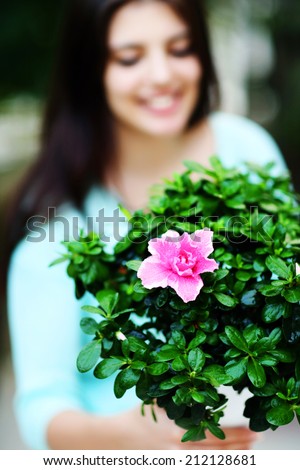 Closeup portrait of a woman holding flower in a pot. Focus on flowers