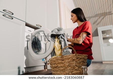 Young hispanic brunette woman putting clothes at washing machine while doing laundry at home Stok fotoğraf © 