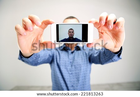 Portrait of a man taking selfie. Focus on smartphone