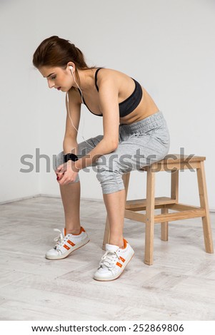 Portrait of a beautiful sports woman sitting on the wooden chair at gym