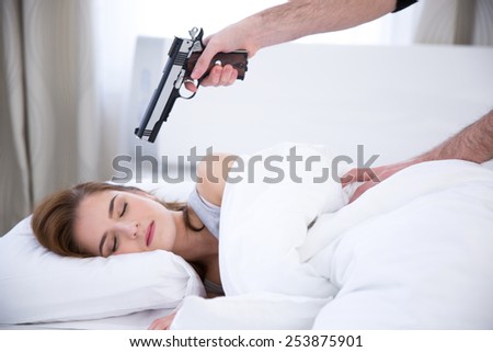 Young woman sleeping while the gun aimed at her