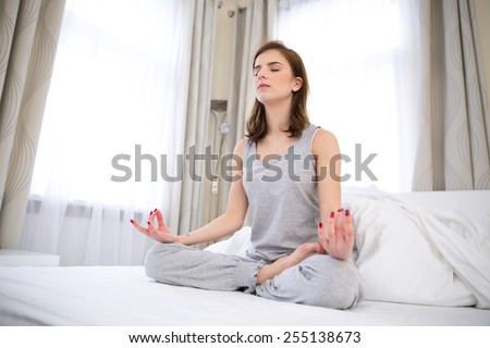 Beautiful woman doing yoga exercises on the bed at home