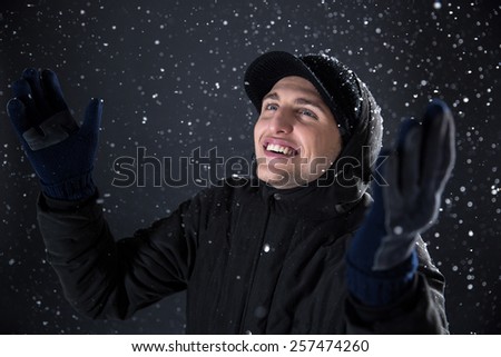 Happy man enjoys snow over black background