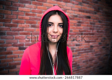Portrait of a sporty woman in headphones over brick wall