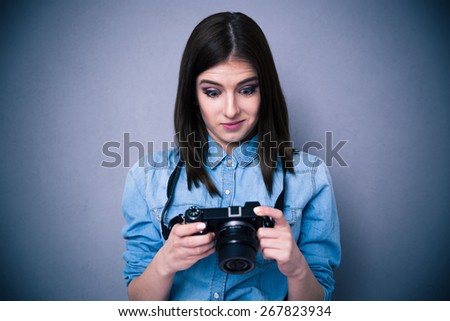 Surprised young woman looking on camera screen over gray background