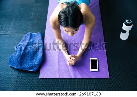 Top view portrait of a young woman doing yoga exercises on yoga mat at gym