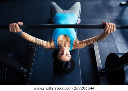 Young fit woman working out with barbell on bench in the gym. Bar Bench Pres