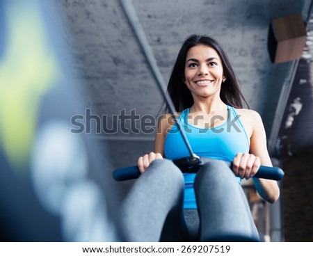 Happy charming woman working out on simulator at gym