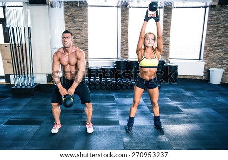 Muscular man and fit woman workout with kettle ball at gym