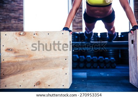Fit woman doing push ups on fit box at gym