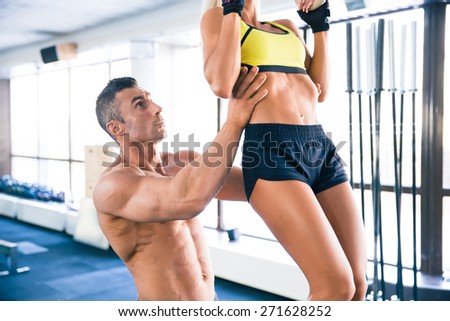 Sporty woman pull-up with coach in gym