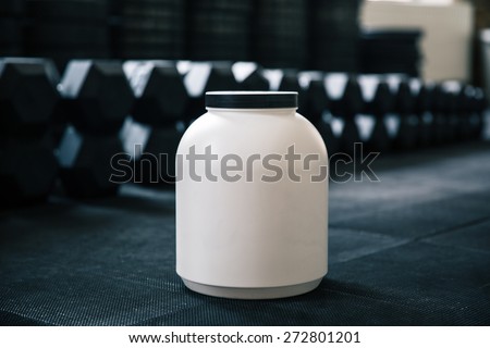 Closeup image of a plastic container with sports nutrition in gym