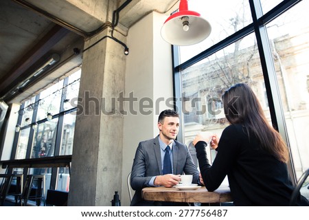 Businesswoman and happy businessman drinking coffee in cafe