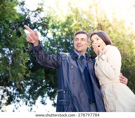 Portrait of a man pointing on something with happy woman in park