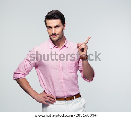 Confident businessman in shirt pointing finger away over gray background. Looking at camera