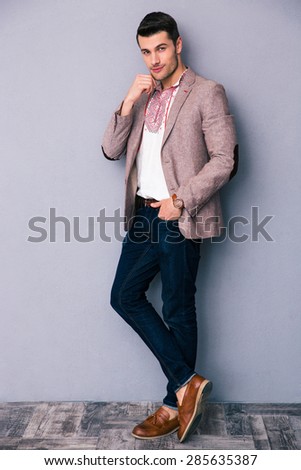 Full length portrait of a fashion man standing over gray background