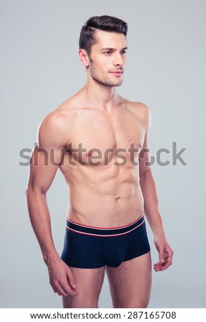 Muscular young man standing over gray background