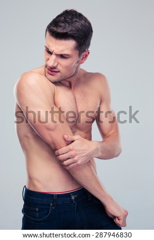 Handsome man having shoulder pain over gray background