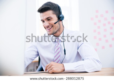 Portrait of a male operator with headset using PC in office