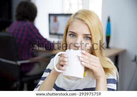 Young casual woman drinking coffee in office