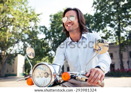 Portrait of a happy stylish man on scooter
