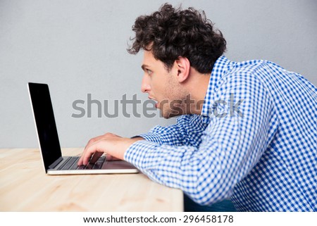 Side view portrait of a casual businessman sitting at the table and using laptop