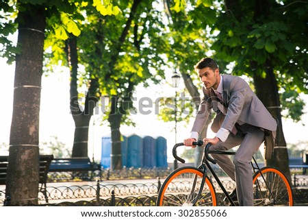 Businessman riding bicycle to work in park in morning